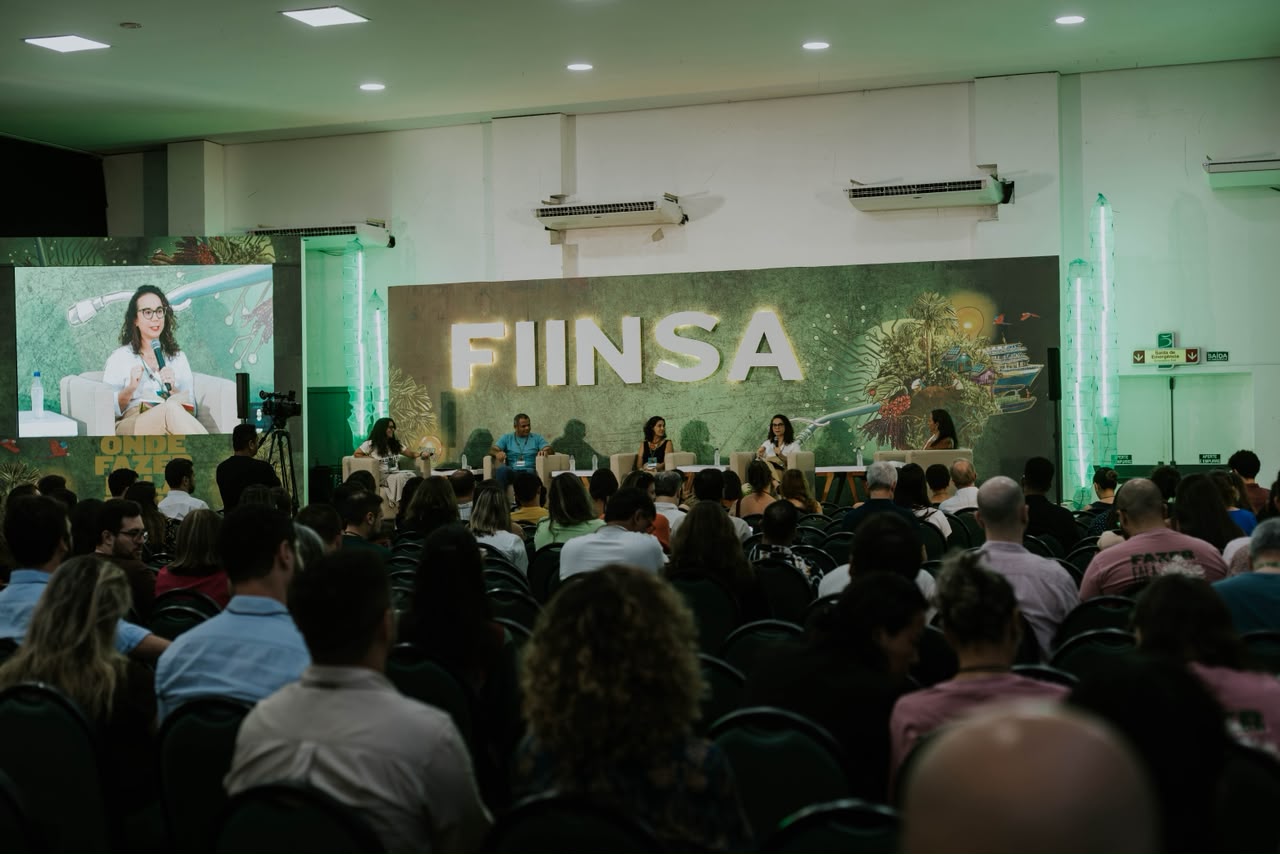 FIINSA reúne em Manaus nomes da economia, do clima e da inovação para discutir o futuro da Amazônia Painel de debate no palco do FIINSA, com letreiro do festival ao fundo, telão e plateia lotada