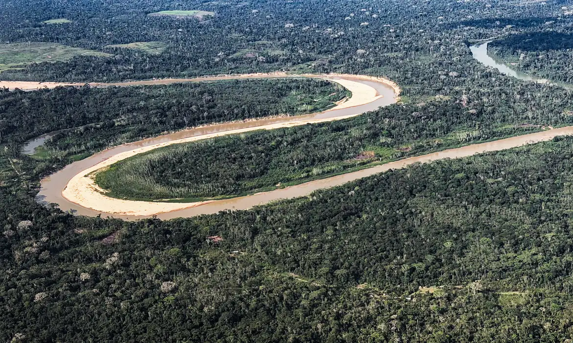 Holanda anuncia investimento de US$ 500 milhões em fundo criado pelo Brasil para proteger florestas tropicais Vista aérea de um rio sinuoso cercado pela Floresta Amazônica, com extensa vegetação nativa preservada.